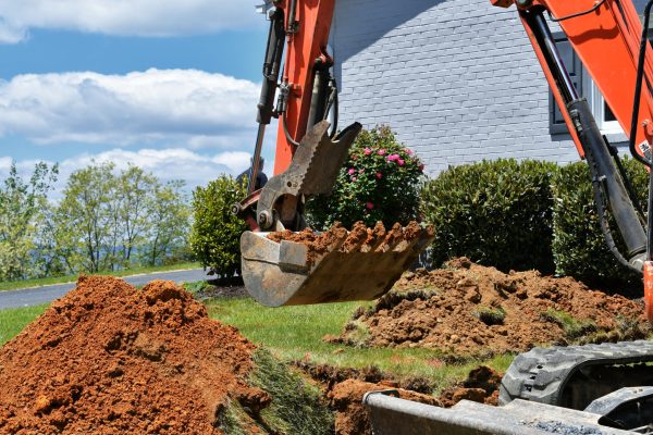 backhoe-digging-dirt-in-lawn-to-install-electrical-2026-01-08-07-12-42-utc