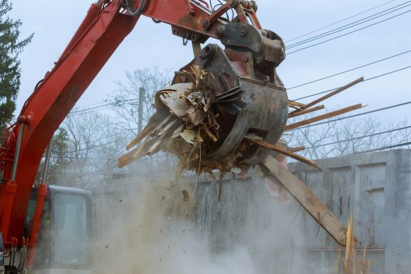 old house being excavator demolished by a large backhoe wooden planks and rubble and the ruins