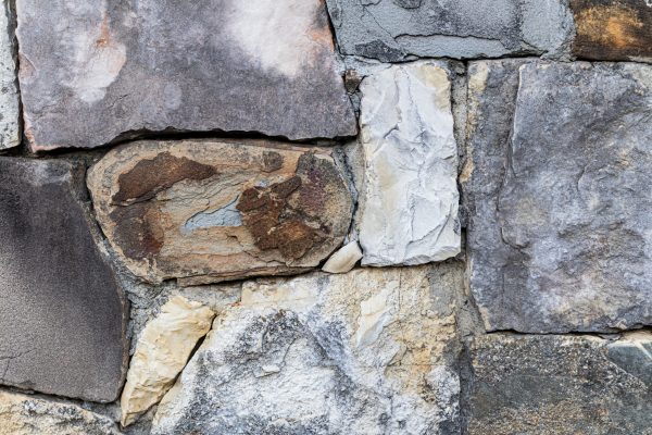 The texture of a large stone wall made of rough stones of different colors. Beautiful natural stone background. wallpaper, layout.